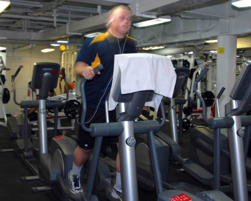 Ein Mann im Fitnessstudio trainiert mit dem Crosstrainer.